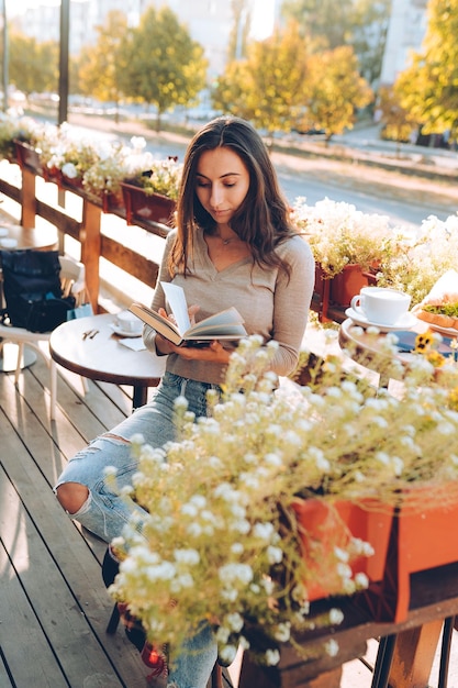 Ritratto di una bella donna che legge un libro mentre si rilassa nel caffè