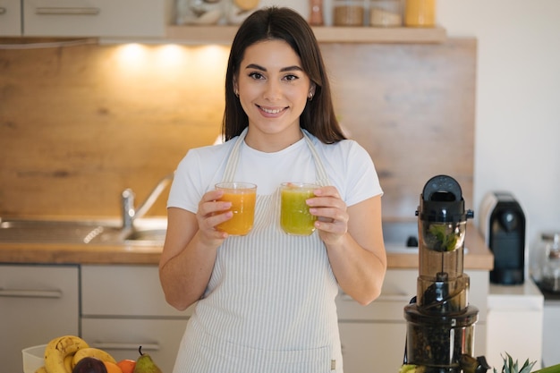 Ritratto di una bella donna che tiene in mano due bicchieri di bevande diverse, una bevanda vegana sana