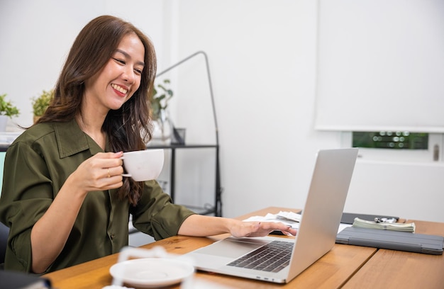 Ritratto di una bella donna che tiene la tazza da caffè a portata di mano durante lo shopping online per le vendite del cyber monday