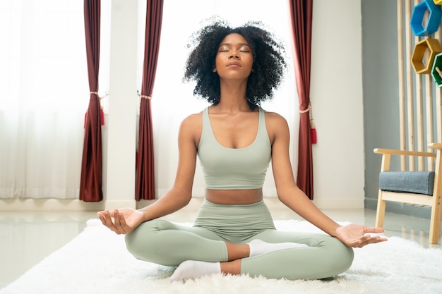 Ritratto di una bella donna con capelli ricci che fa yoga a casa