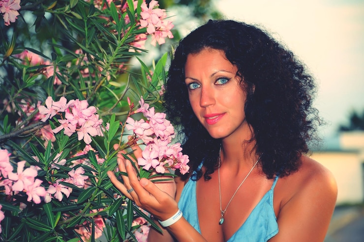 Foto ritratto di una bella donna con fiori rosa che fioriscono sulla pianta