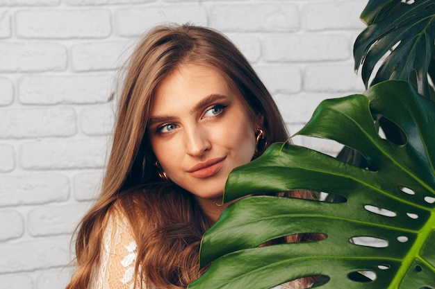 Ritratto di una bella donna con foglie di monstera. Foto creativa