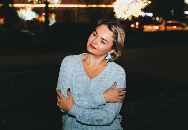 Ritratto di una bella donna con i capelli corti che guarda la telecamera per strada di notte con luci intense