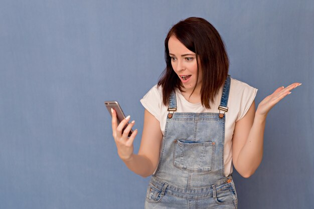 Ritratto di una bella donna con un telefono in mano. Emozioni diverse di una ragazza.