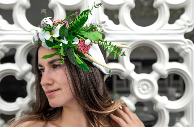 Ritratto di una bella donna con una composizione di fiori naturali sulla sua testa da vicino.