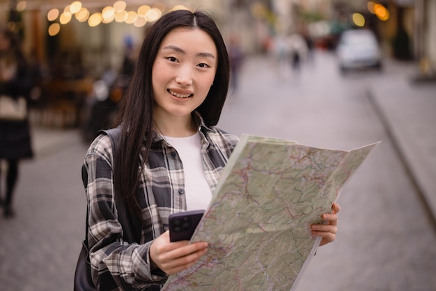 Ritratto di una bella donna coreana bruna che tiene una mappa per le strade della città vecchia Donna asiatica turista o donna d'affari che viaggia in Europa