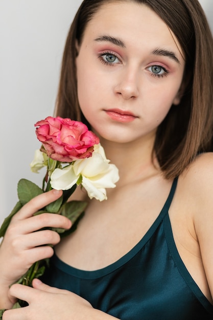 Ritratto di una bella donna dai capelli scuri con fiori. Foto di moda, graziosa bambina con rosa rosa