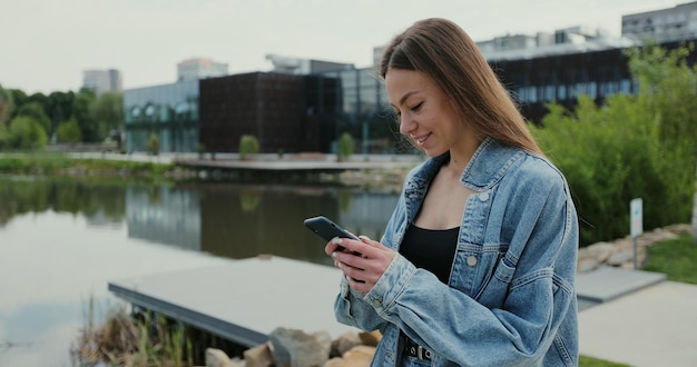 Ritratto di una bella donna in abiti casual e che utilizza lo smartphone per strada Donna che utilizza la messaggistica online del telefono e naviga in Internet