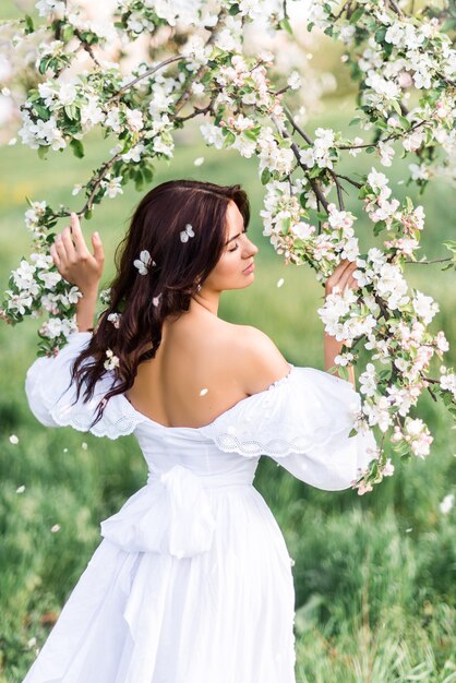 Ritratto di una bella donna in un giardino fiorito. Una ragazza in un giardino primaverile. foto dal retro ..