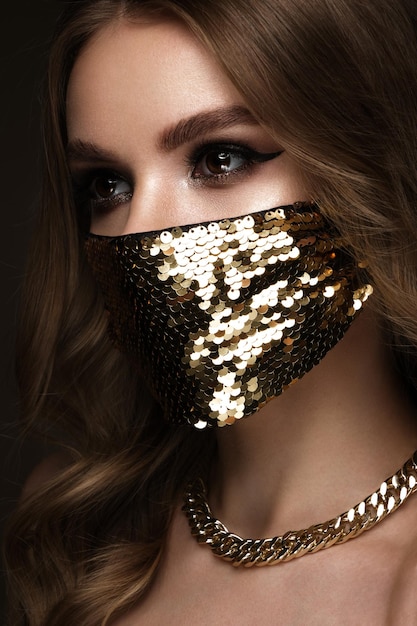 Ritratto di una bella donna in una maschera d'oro con paillettes e trucco classico Modalità maschera durante la pandemia covid