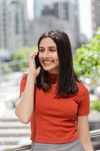 ritratto di una bella donna indiana sorridente che parla al cellulare e risponde alla chiamata guardando lontano