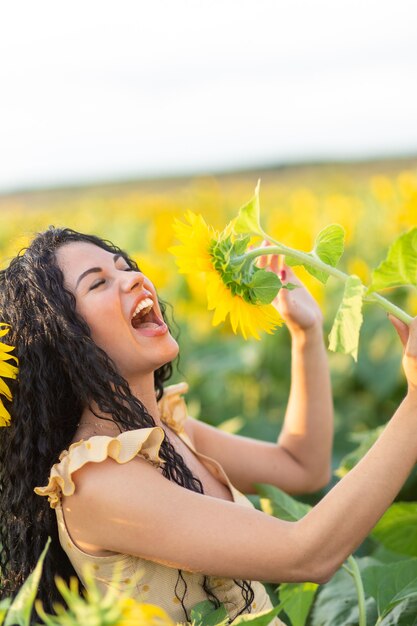 Ritratto di una bella donna mora sorridente che usa un girasole come microfono e canta