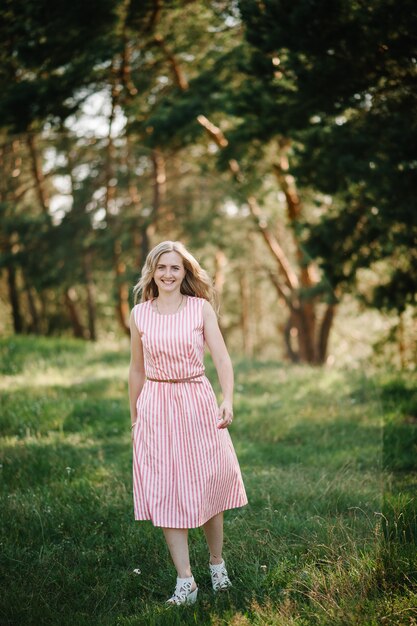 Ritratto di una bella donna scappare nell'erba verde sul campo, la natura durante le vacanze estive. Il gioco nel parco all'ora del tramonto. Avvicinamento.