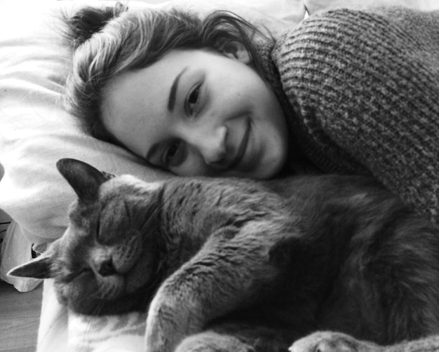 Ritratto di una bella donna sdraiata a letto con un gatto a casa