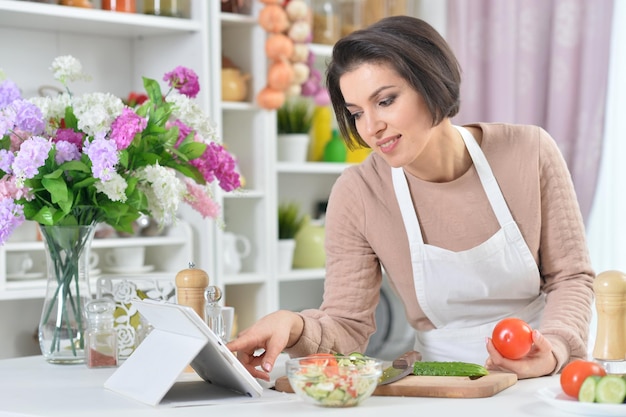 Ritratto di una bella donna sorridente che cucina in cucina