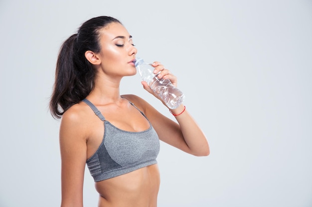 Ritratto di una bella donna sportiva acqua potabile isolata su un muro bianco