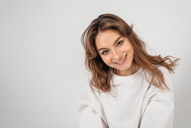 Ritratto di una bella donna su sfondo bianco sorridente e guardando la telecamera attraverso le dita