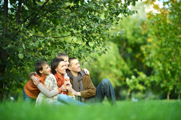 Ritratto di una bella famiglia felice seduta nel parco autunnale