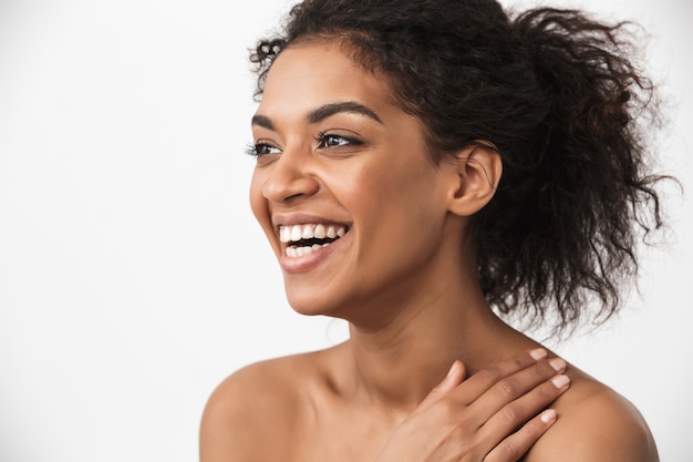 ritratto di una bella giovane donna africana ridendo felice in posa isolato su muro bianco.