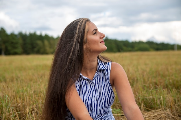 ritratto di una bella giovane donna caucasica bruna su uno sfondo di un campo, la natura. sorridente felice giovane adulto