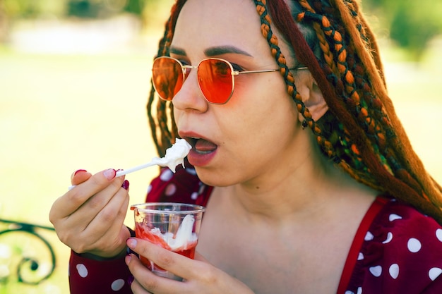 Ritratto di una bella giovane donna che mangia il gelato nel parco