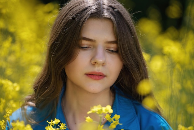 Ritratto di una bella giovane donna circondata da fiori di colza