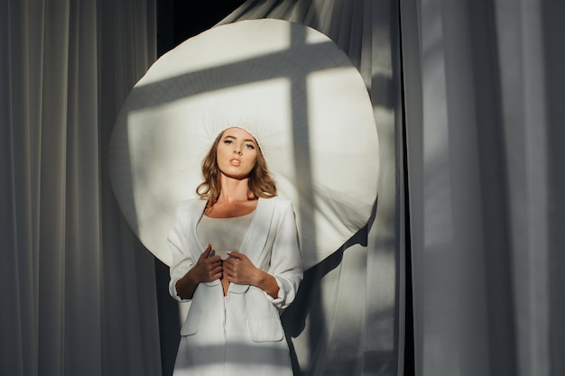 Ritratto di una bella giovane donna in stile retrò con un elegante cappello bianco e vestito