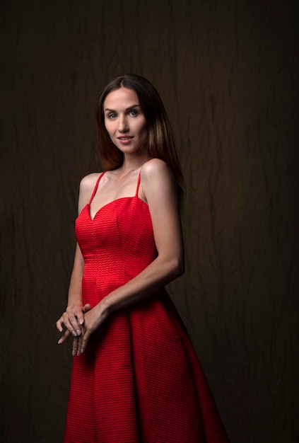 ritratto di una bella giovane donna in un abito rosso girato in studio su uno sfondo scuro