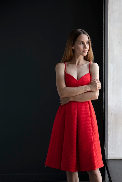 ritratto di una bella giovane donna in un vestito rosso, girato in studio su uno sfondo scuro