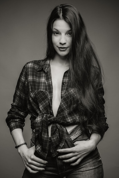 Ritratto di una bella giovane modella in piedi su uno sfondo grigio