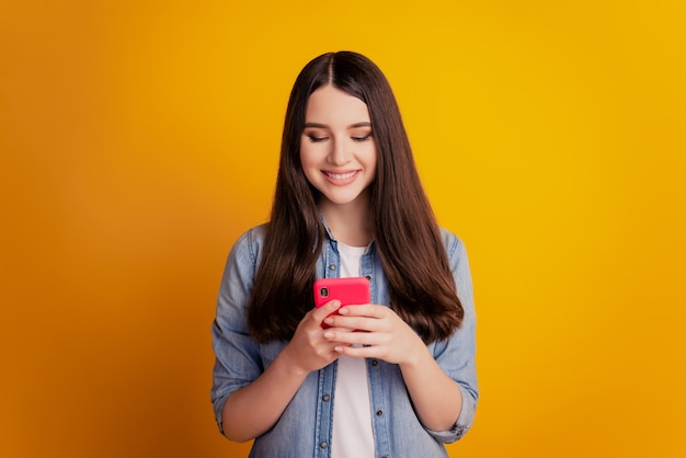 Ritratto di una bella ragazza allegra che tiene in mano lo smartphone guarda lo schermo chiacchierando con un sorriso a trentadue denti