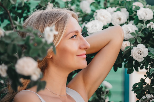 Ritratto di una bella ragazza bionda con acconciatura di un cespuglio di rose bianche. Sessione fotografica di matrimonio