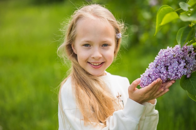 Ritratto di una bella ragazza bionda con un lilla viola nelle sue mani