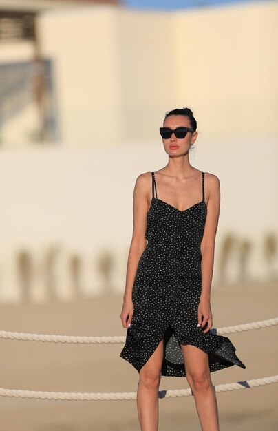 ritratto di una bella ragazza bruna in occhiali da sole in un vestito nero in estate