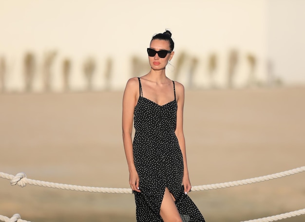 ritratto di una bella ragazza bruna in occhiali da sole in un vestito nero in estate