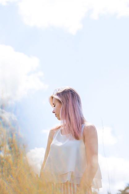 Ritratto di una bella ragazza che balla con i capelli rosa contro il cielo blu