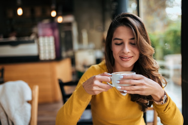 Ritratto di una bella ragazza che beve tazza di caffè.