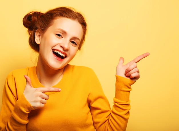 Ritratto di una bella ragazza che punta il dito lontano sul bac giallo