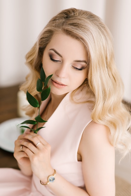 Ritratto di una bella ragazza con i capelli biondi ricci in un abito delicato. Gli occhi guardano dall'alto in basso con il bello primo piano di trucco