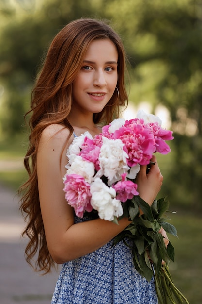 Ritratto di una bella ragazza con un mazzo di fiori estivi. camminare in città. sfondo sfocato