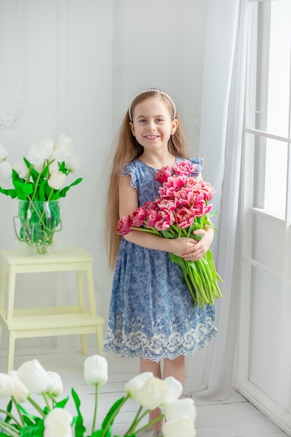 Ritratto di una bella ragazza dagli occhi azzurri piccola tra i fiori di primavera Festa della mamma Festa della donna Pasqua