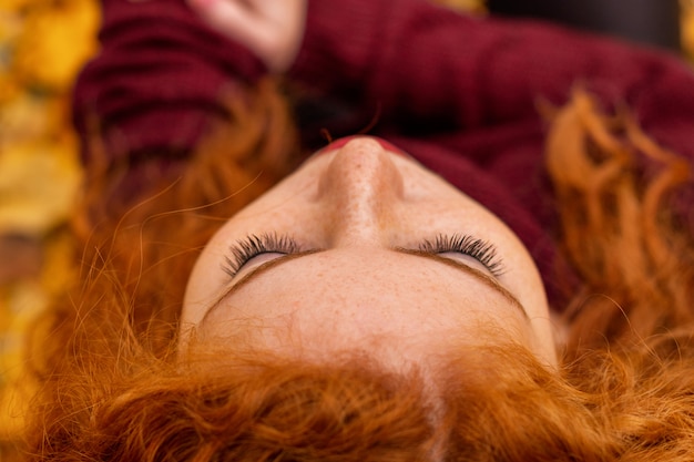 Ritratto di una bella ragazza dai capelli rossi in foglie gialle