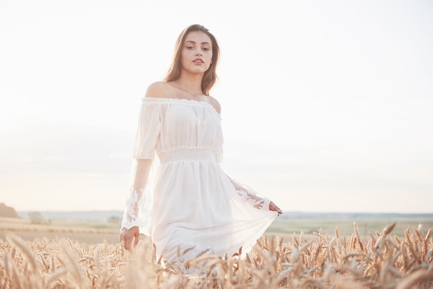 Ritratto di una bella ragazza in abito bianco nel campo di grano