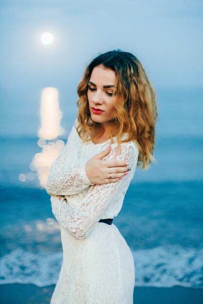 Ritratto di una bella ragazza in abito bianco sulla spiaggia