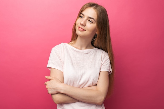 Ritratto di una bella ragazza in piedi da un muro rosa