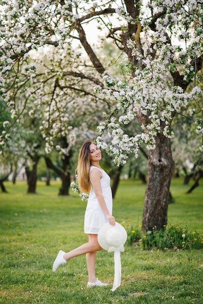 Ritratto di una bella ragazza in un frutteto di mele in fiore in primavera