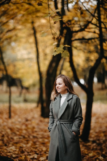 ritratto di una bella ragazza in un parco autunnale con un cappotto