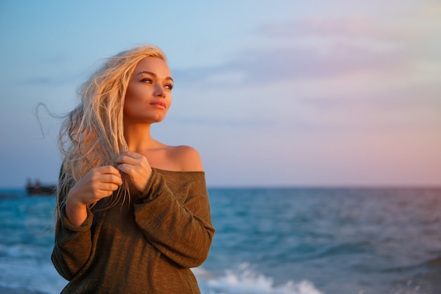 Ritratto di una bella ragazza sulla spiaggia al tramonto.