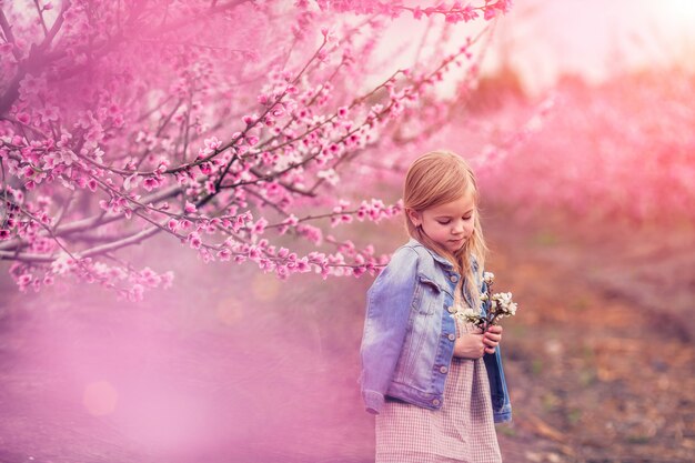 Ritratto di una bella ragazza vicino a un albero in fiore di mandorle e lillà