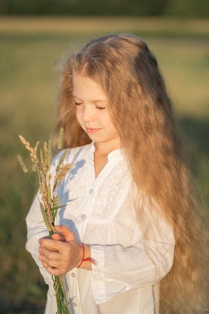 Ritratto di una bella ragazzina con i capelli biondi il bambino cammina nel campo e raccoglie